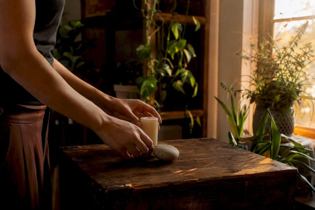 Hands performing small identity ritual with stone and candle