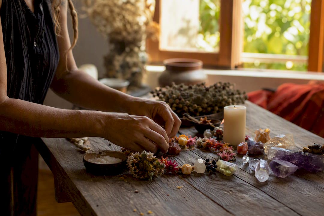 Hands cleaning ritual altar with candles and crystals