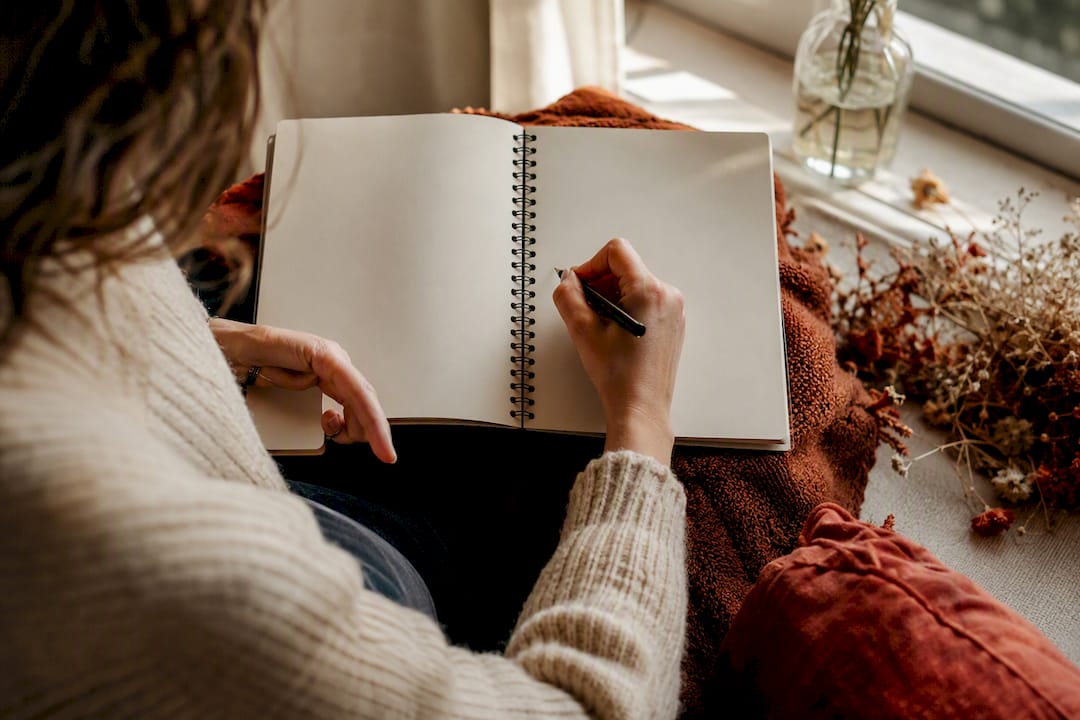 Hands writing CBT journal two-column log