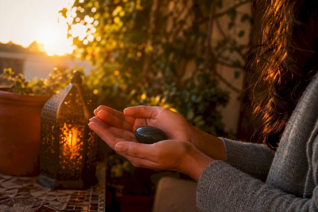 Hands holding worry stone by candlelight