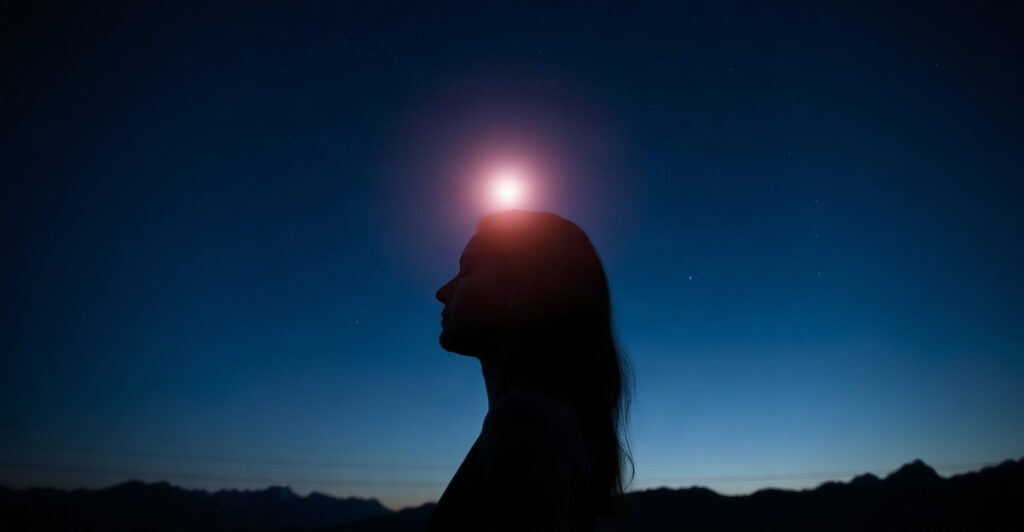 A woman meditating at twilight with a soft glow at her forehead, illustrating how to open your third eye